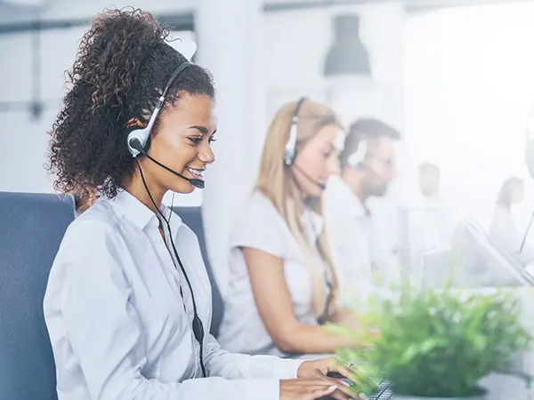 A customer service representative talks on a headset while typing on the computer.