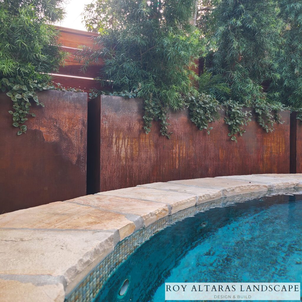 Corten planters line the edges around a pool and overflow with green plants.