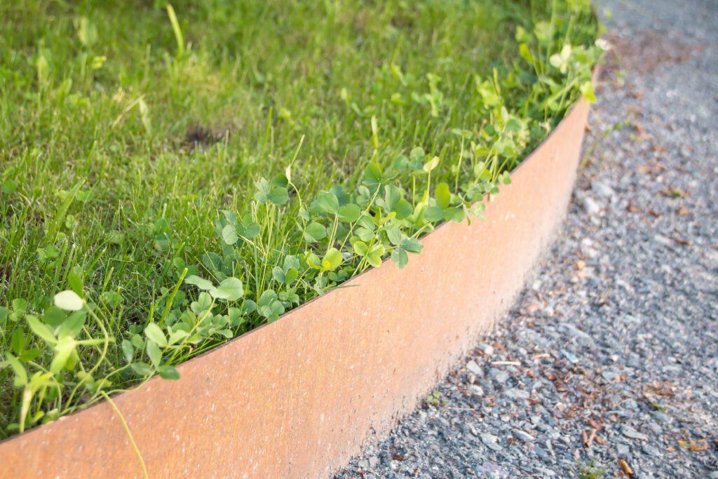 Corten steel edging separates grassy and gravel areas.