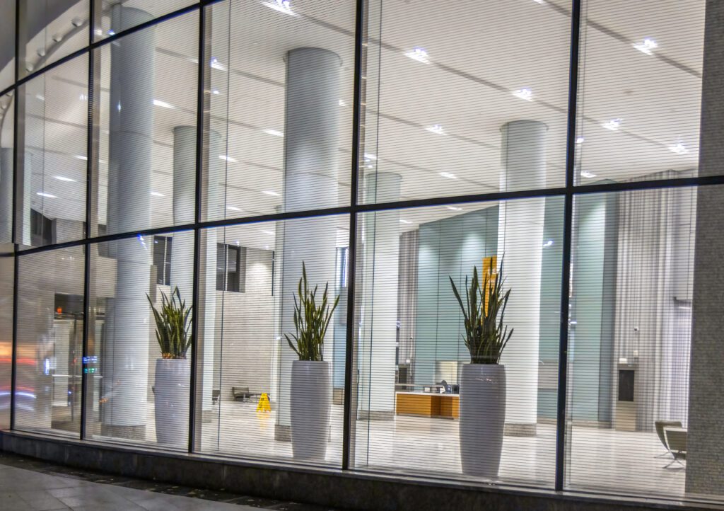 Three aluminum planter pots with plants growing inside a business lobby.